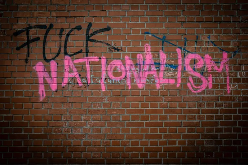 A brick wall with grafitti that reads 'fuck nationalism'.