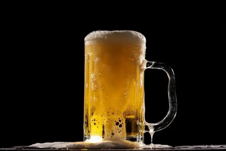 A stein of golden beer against a black background