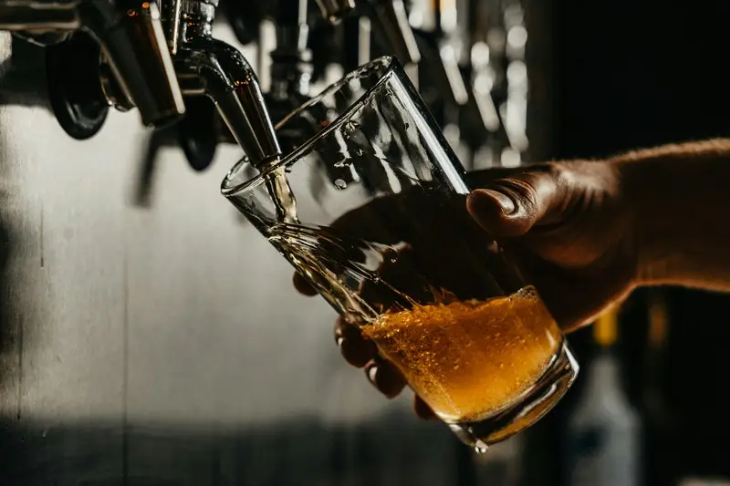 A pint of beer being poured from a beer tap
