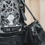 A person viewed from behind weraing a leather jacket sporting a pentagram and the words 'the devil'