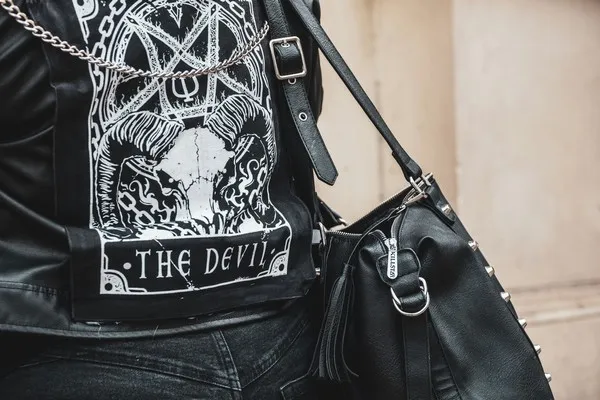 A person viewed from behind weraing a leather jacket sporting a pentagram and the words 'the devil'