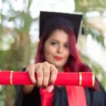 A females university graduate holding her credentials to the camera