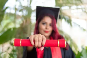 A females university graduate holding her credentials to the camera