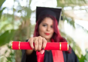 A females university graduate holding her credentials to the camera