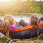 two children enjoying leisure time in a hammock by a lake