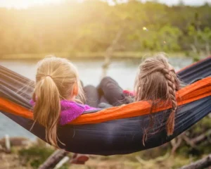 two children enjoying leisure time in a hammock by a lake