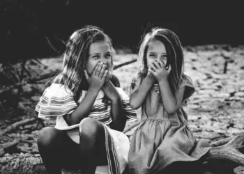 A black and white shot of two girls giggling behind their hands