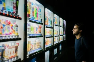 A man stood at a japanese vending machine partaking in decision-making.