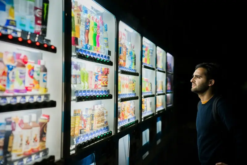 A man stood at a japanese vending machine partaking in decision-making.