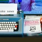 A typewriter typing out the words 'fake news' alongside some books with the same title