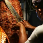 A man slicing meat from a doner kebab