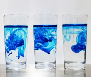 Three glasses each with a blue food dye swirling around