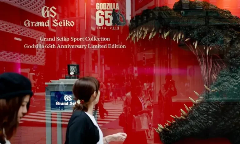 A woman wlaking past a window advertisment for godzilla