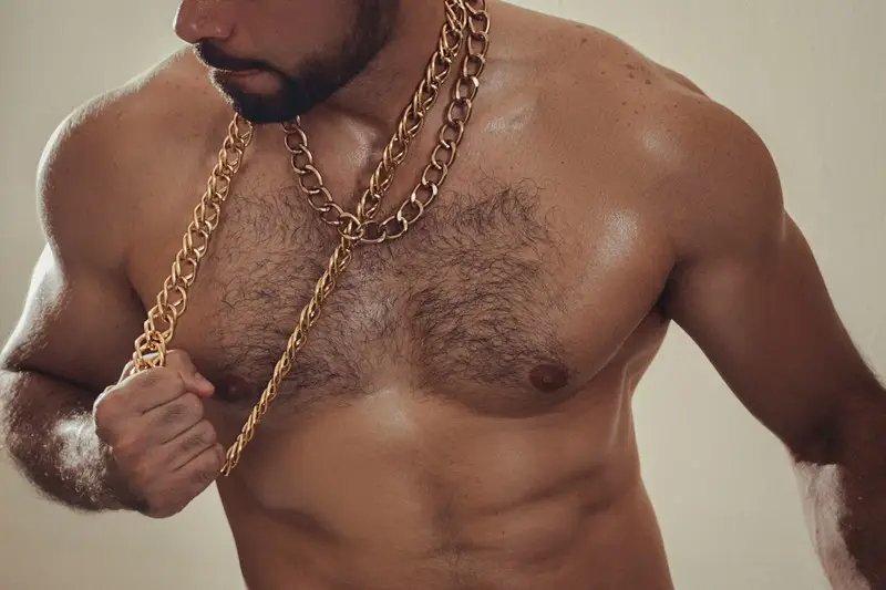 A topless, ripped geezer pulling on his gold chain
