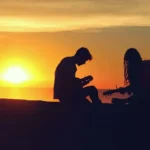 A silhouette of a couple playing instruments at sunset