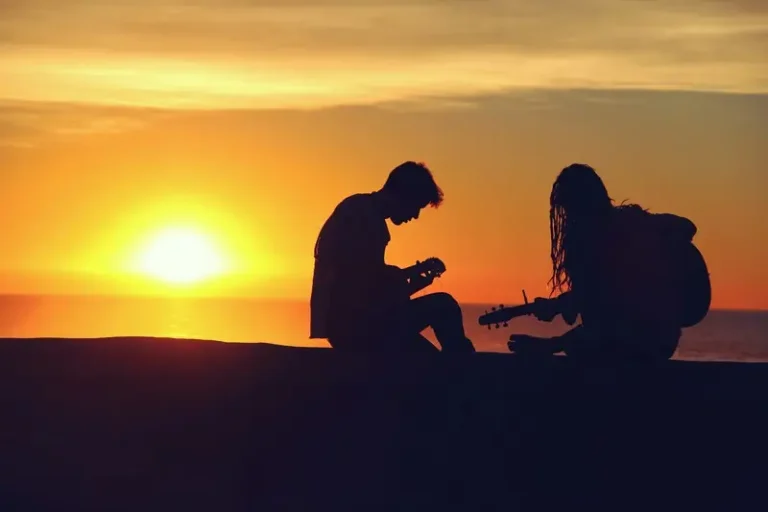 A silhouette of a couple playing instruments at sunset