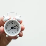 A miniature white alarm clock