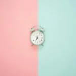 An alarm clock against a background of pastel pink and blue