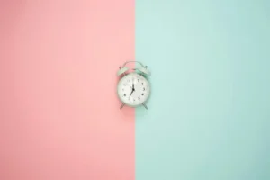 An alarm clock against a background of pastel pink and blue