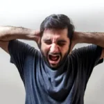 A man with his hands behind his head showing frustration