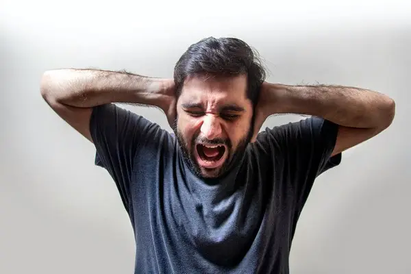A man with his hands behind his head showing frustration