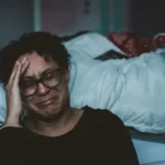 A woman crying next to a bed