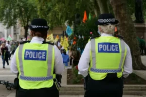 Two british police viewed from behind wearing yellow vests