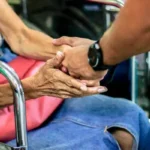 A social worker holding hands with an older person