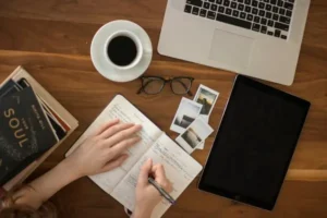 A hand writing in a journal on a wooden table