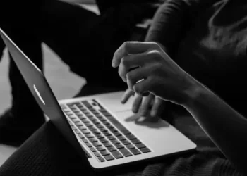 Somebody typing an essay on a laptop in black and white