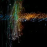 An abstract squiggley image of many colours against a black backgorund