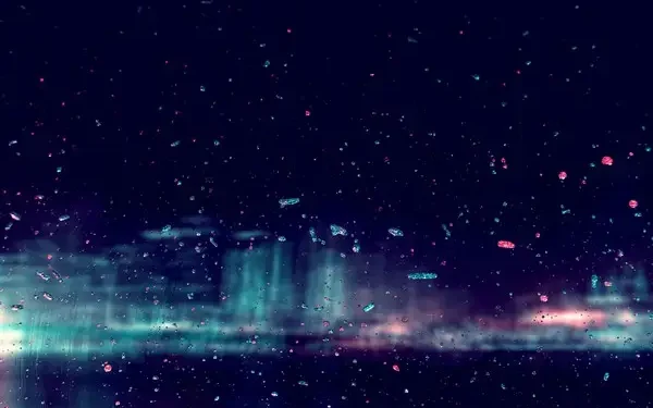 an abstract image of a blurred city at night viewed through raindrops on a window