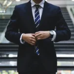 An oligarch fiddling with his suit jacket whilst running an oligopoly