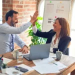 a male and female employee sat at a table doing a high five