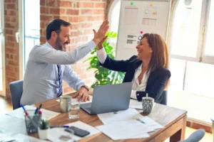a male and female employee sat at a table doing a high five
