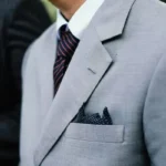 A man in a grey suit and white collared shirt