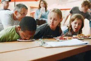 Kids having a school dinner with one kid putting their head in their food
