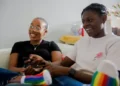 Two black lesbians sat in chairs smiling and laughing