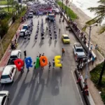 People walking down the street eac holding an individual letter spelling pride