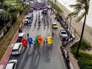 People walking down the street eac holding an individual letter spelling pride