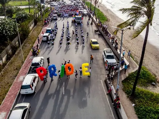 People walking down the street eac holding an individual letter spelling pride