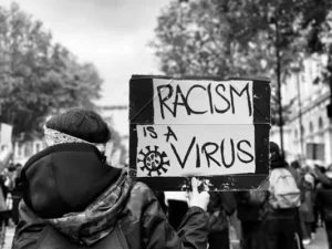 Black and white shot of a protest placard which reads "racism is a virus".