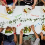 Plates on a white table with welcome words from various languages