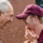 A man caring for a disabled yound person. both are laughing.