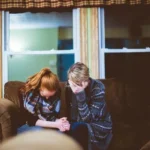 Two women sat on a couch crying