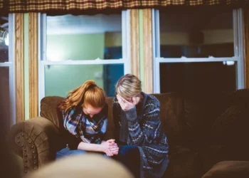 Two women sat on a couch crying