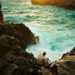 A man enjoying leisure by sitting on rocks at the sea