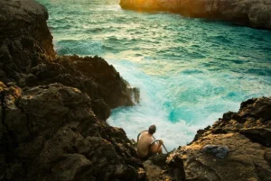 A man enjoying leisure by sitting on rocks at the sea