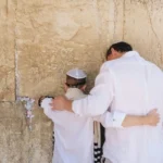 A boy and his father facing a wall during a bar mitzvah, an experience of liminality.