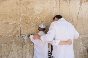 A boy and his father facing a wall during a bar mitzvah, an experience of liminality.